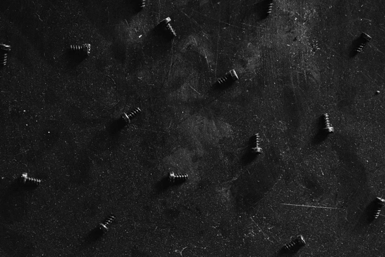 a black and white image of screws and nails on a black background