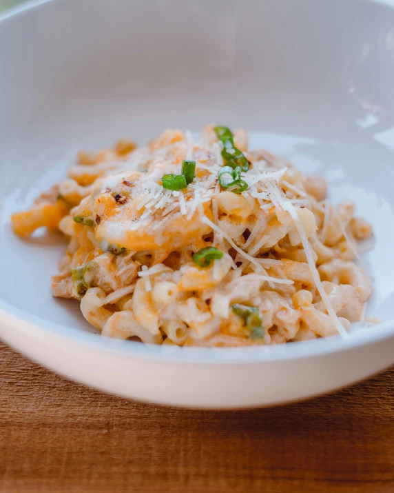 white bowl full of noodles with peas and cheese on top