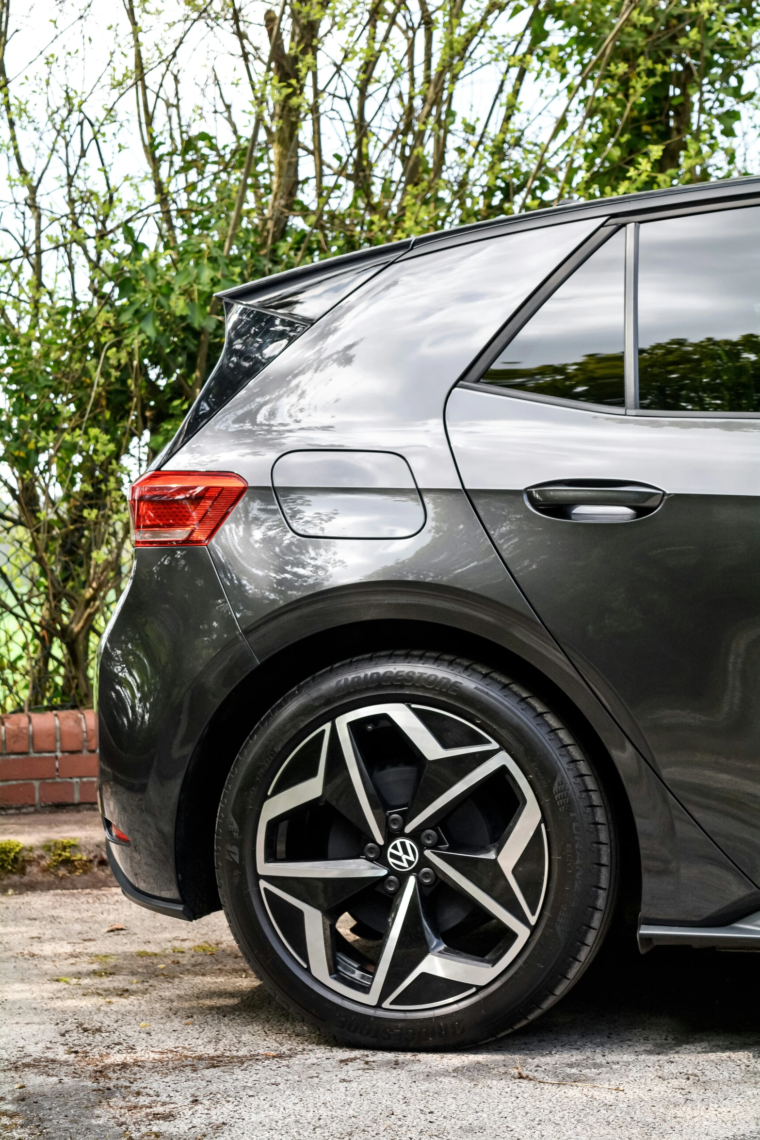 the rear end of a silver car on a cobblestone driveway