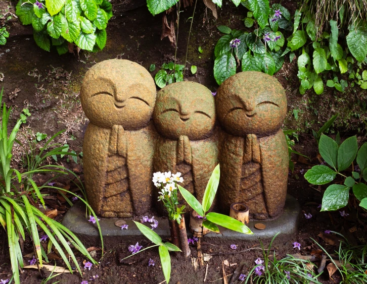 three small statues sitting in a planter