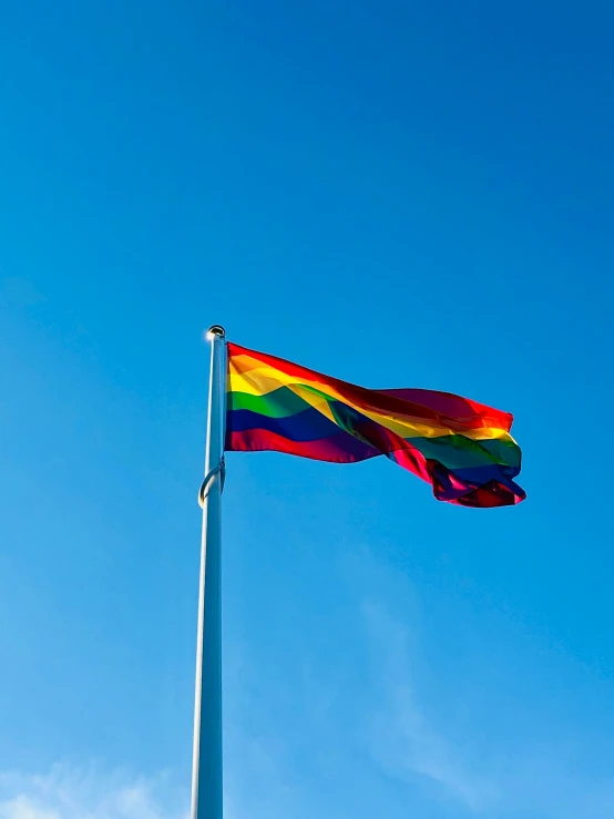 the rainbow flag flies high in the sky