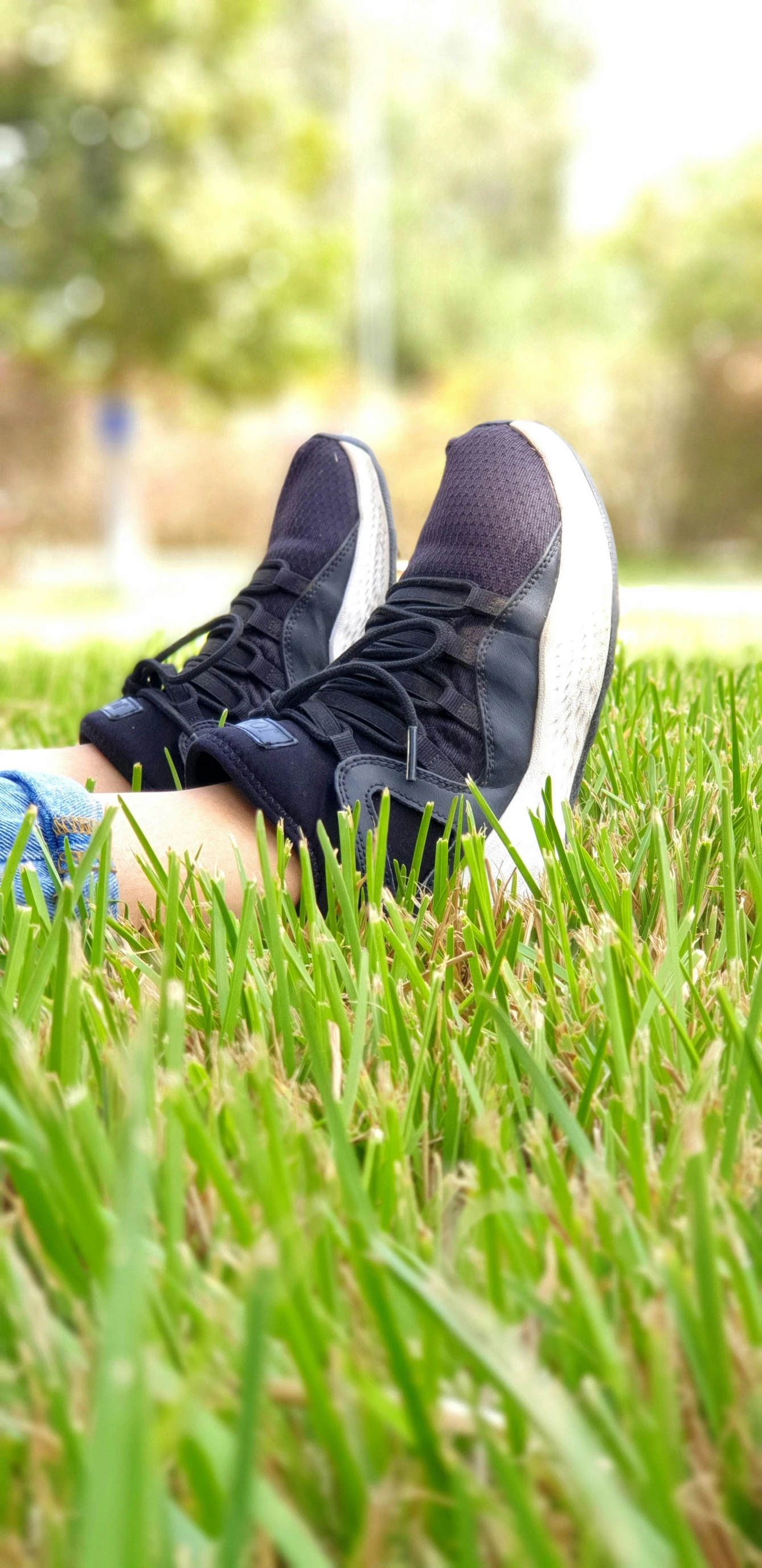 a person in sneakers sits in the grass