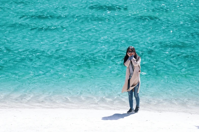 a person standing on a beach by the water