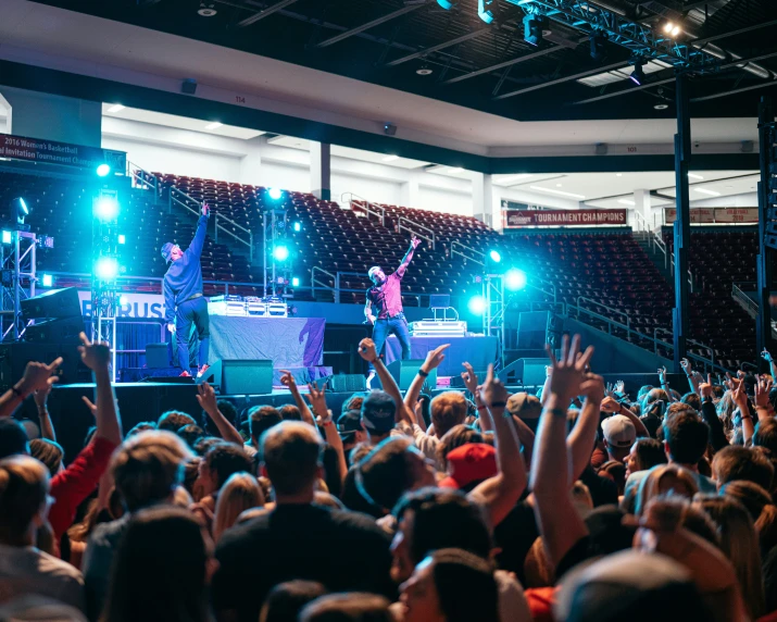 people in a big building, some with their hands up and some on stage