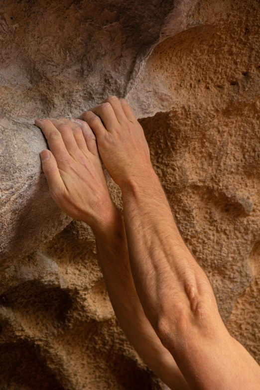 someones hands and bare arms resting on the edge of a rock