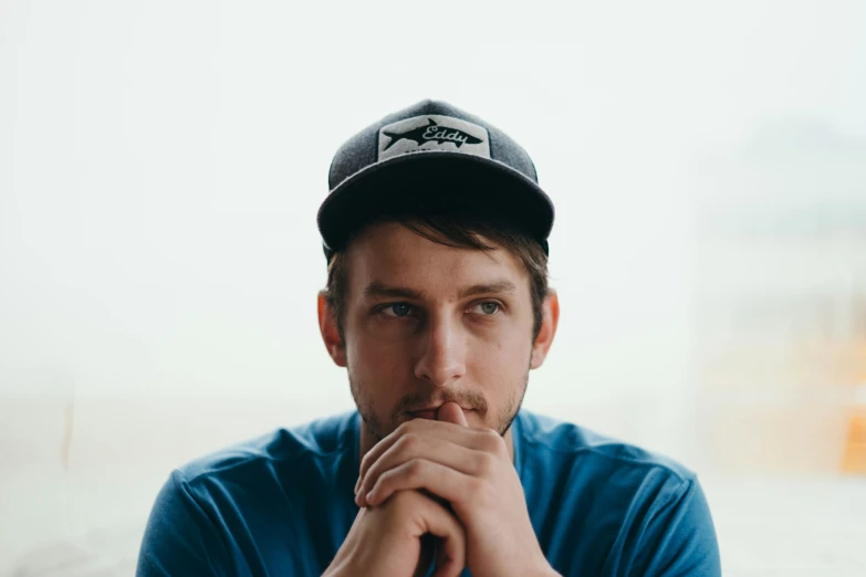 a young man wearing a baseball cap posing for the camera