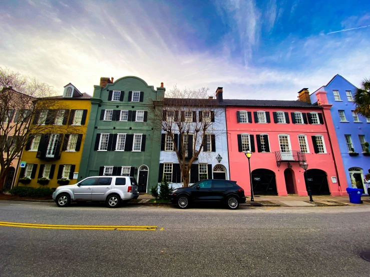 a city street with colorful buildings, parked cars and a truck