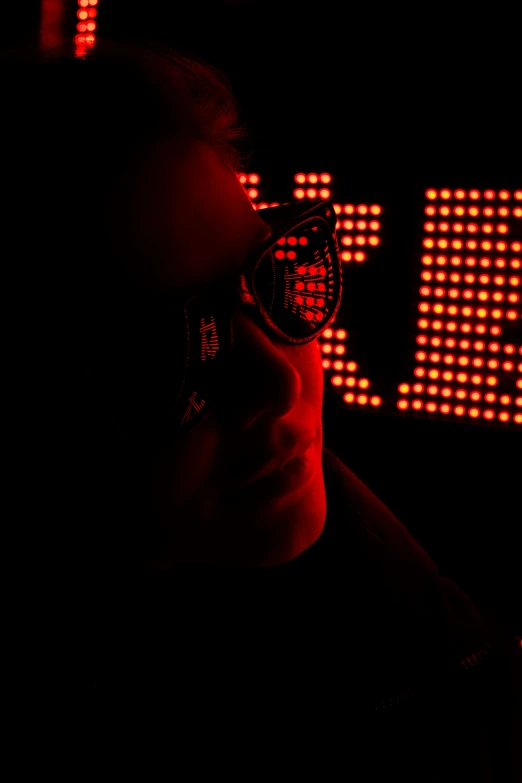 a woman wearing glasses in front of a lit up sign