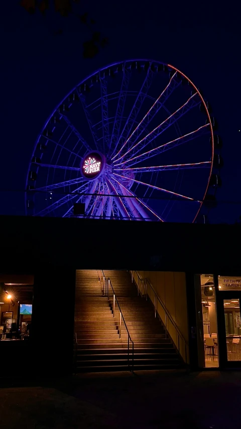 a large ferris wheel near steps lit up at night