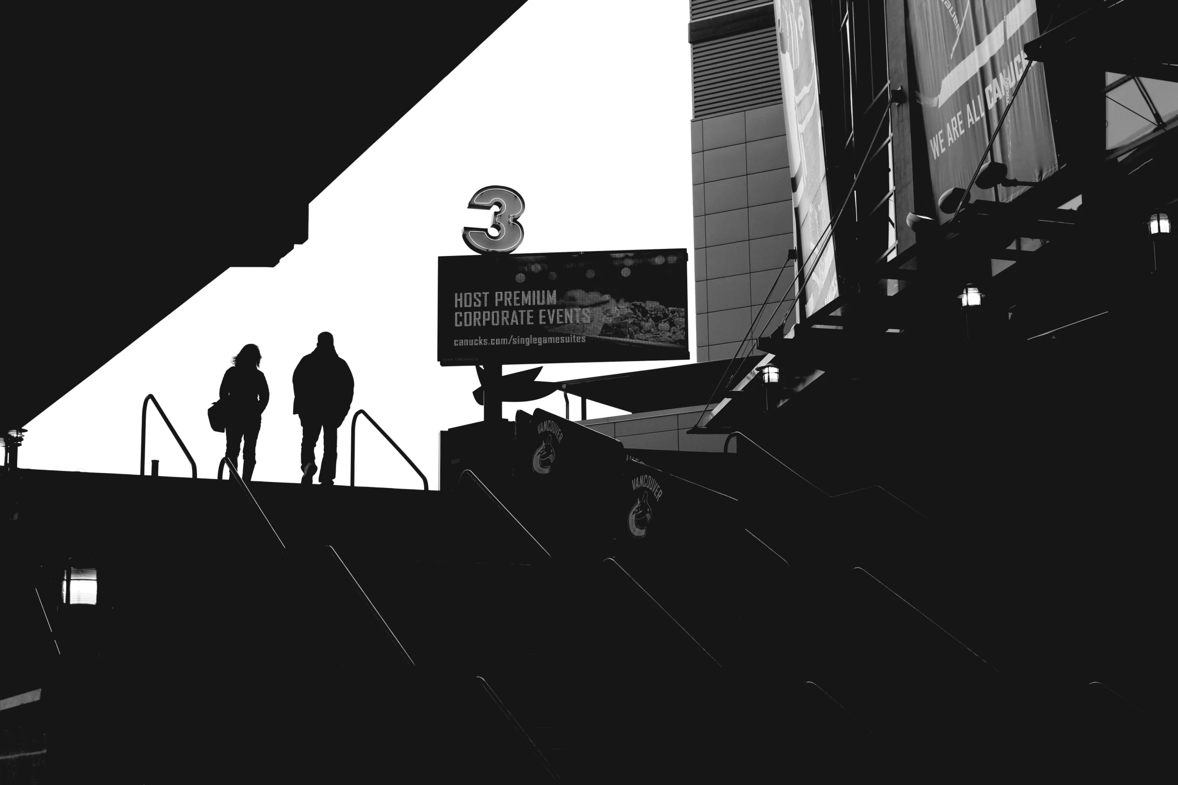 two people are walking up an escalator towards the train station