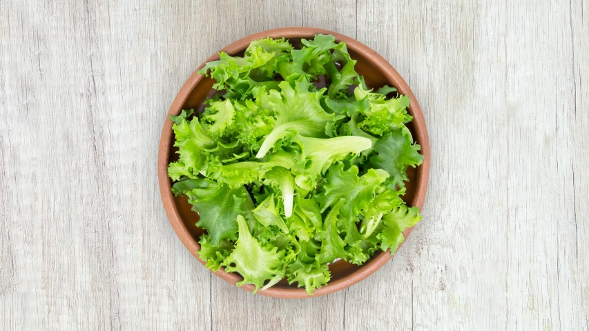 a small bowl of lettuce sits on top of a table