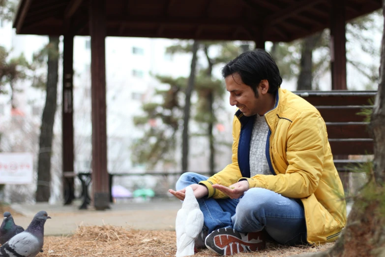 a person sitting on a ground near a bird