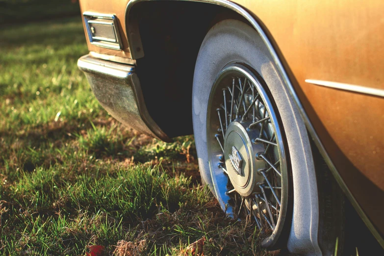 a brown car with black wheels is parked on the grass