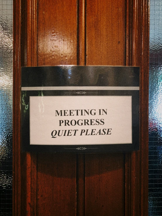 the door to a building has a sign that says, meeting in process quit please