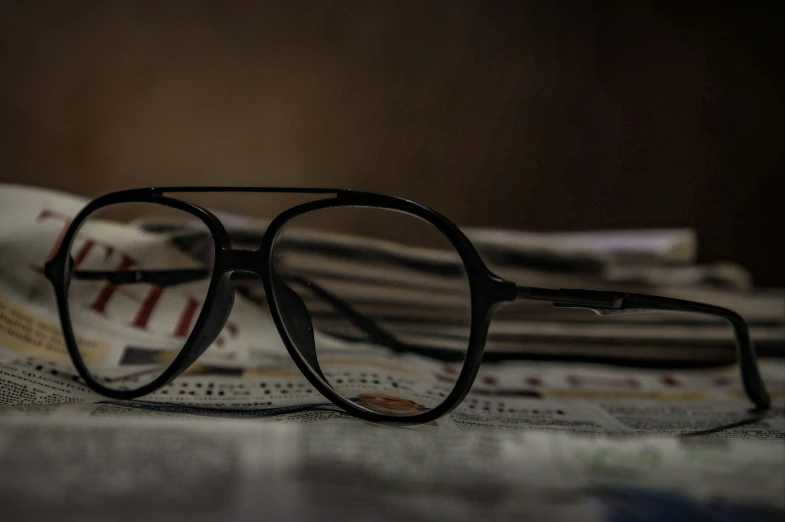 an eyeglass sits on top of the newspaper
