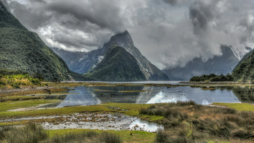 there are clouds in the sky over water and mountains