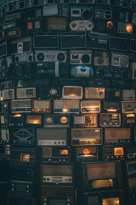 a large stack of old stereo's sitting on the wall