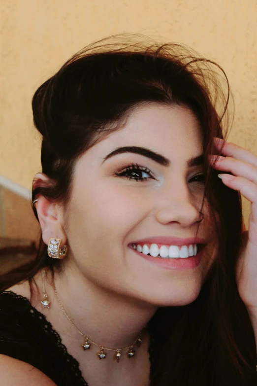 a woman wearing earrings smiling while wearing pearls