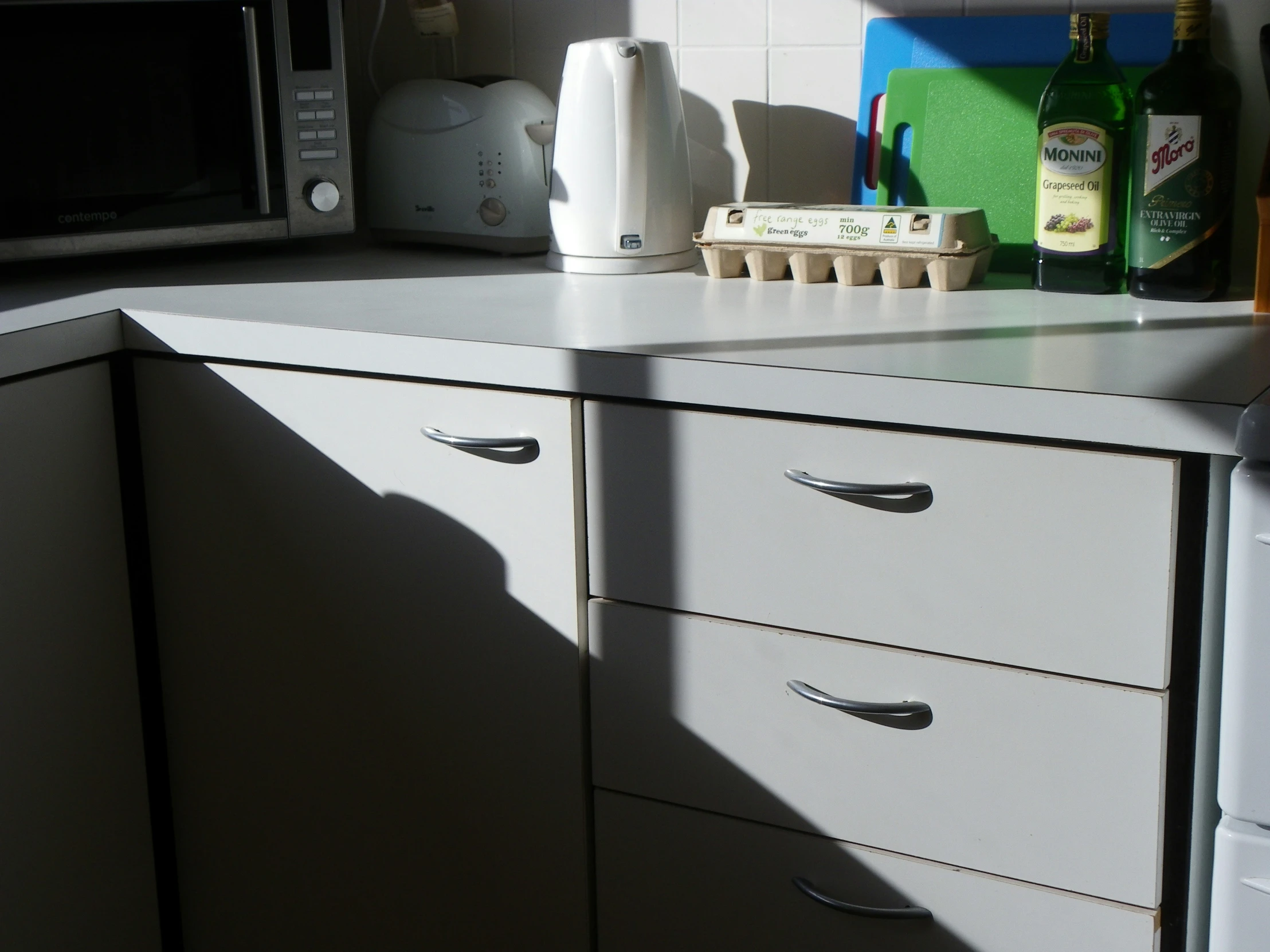 a microwave on a cabinet next to a counter with drawers