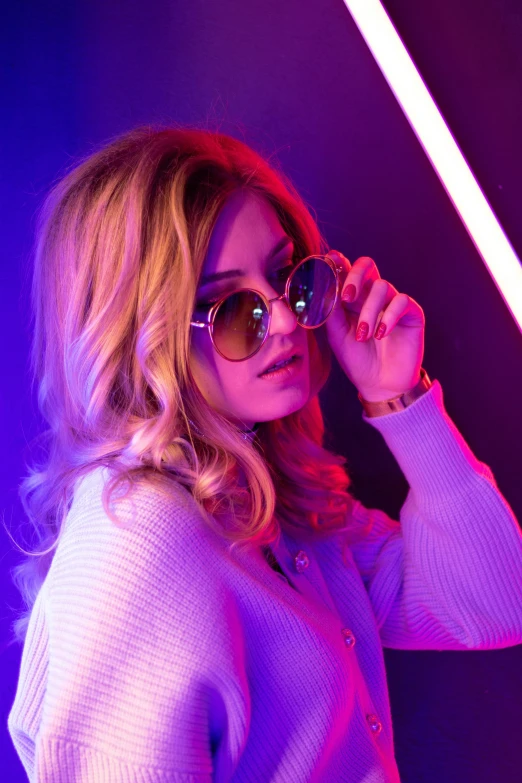 a beautiful woman wearing sunglasses while standing in a neon room