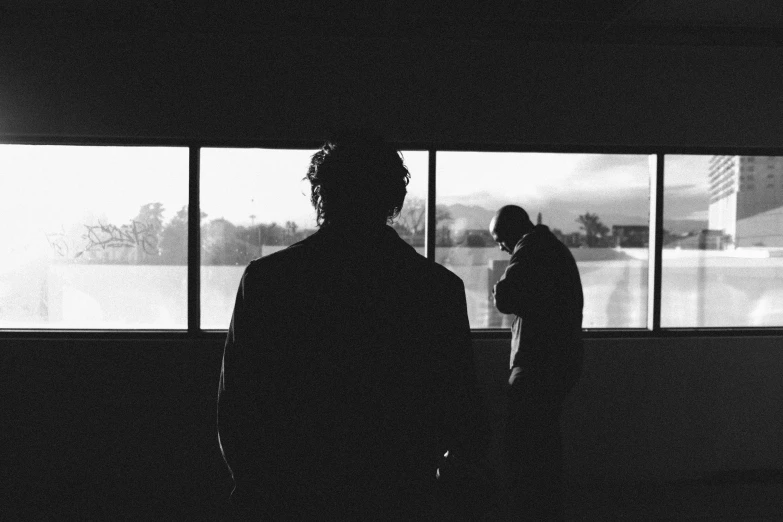 two people in a room looking out a window at snow