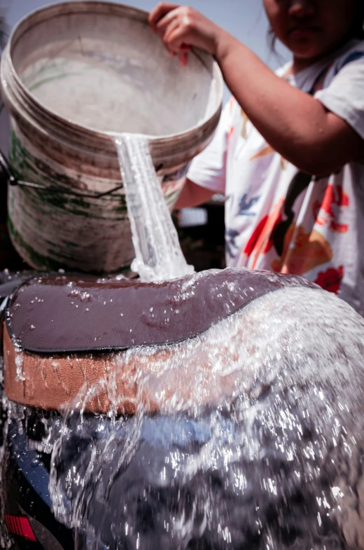 a woman washing the dishes on the water bucket