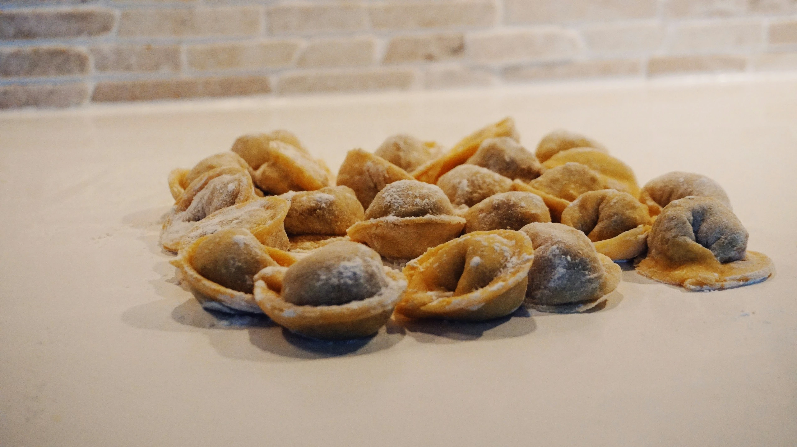 a pile of breaded pastry sits on a table next to a brick wall