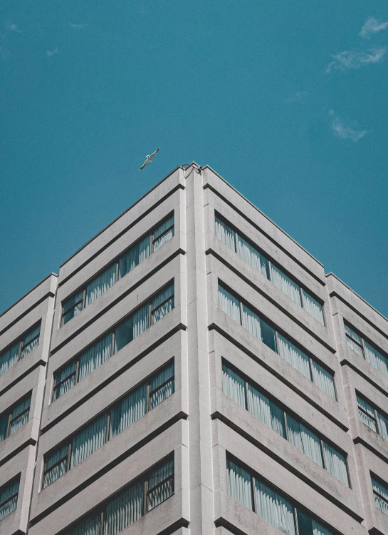 an airplane flying by some gray building