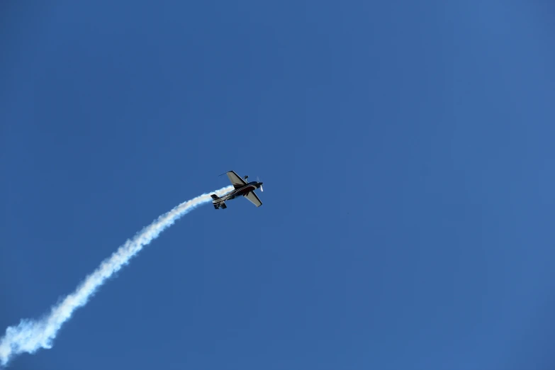 a airplane with smoke coming out of its back flies overhead