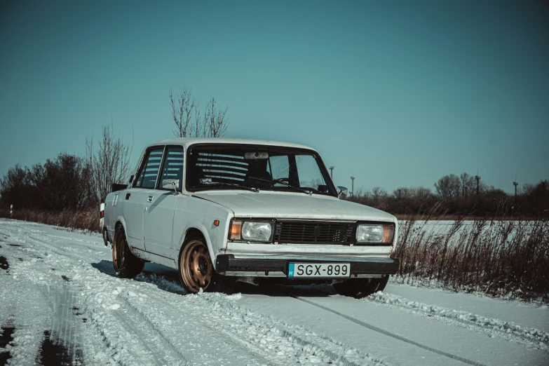 a small white car parked on top of snow covered ground