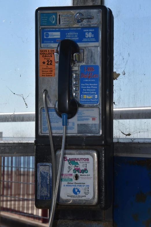 an old phone attached to a pole by some windows