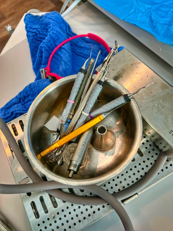 a stainless bowl filled with tools and a blue ball of yarn