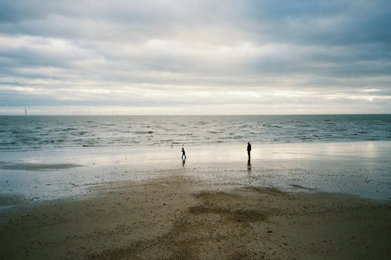 two people stand on the edge of the beach
