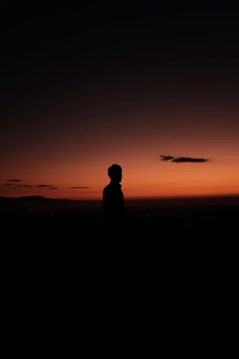 a person standing alone and looking at a sunset
