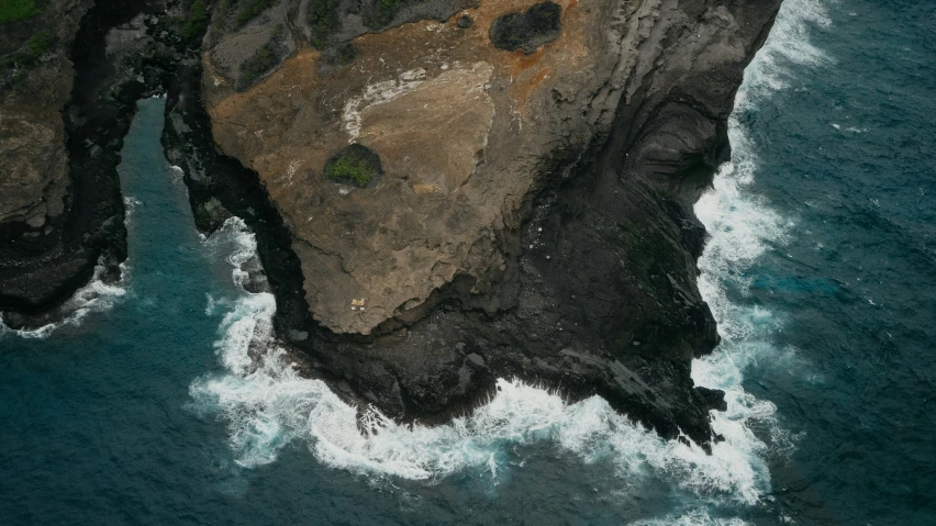 a large rock with small white clouds and water