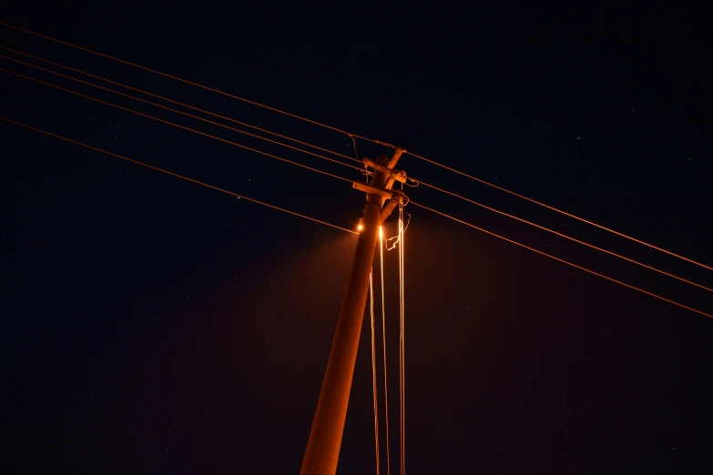 two electric poles are in the dark and are lighted up