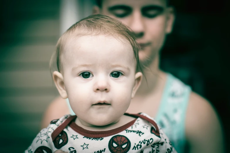 a man holding a little boy with his hand on his chest