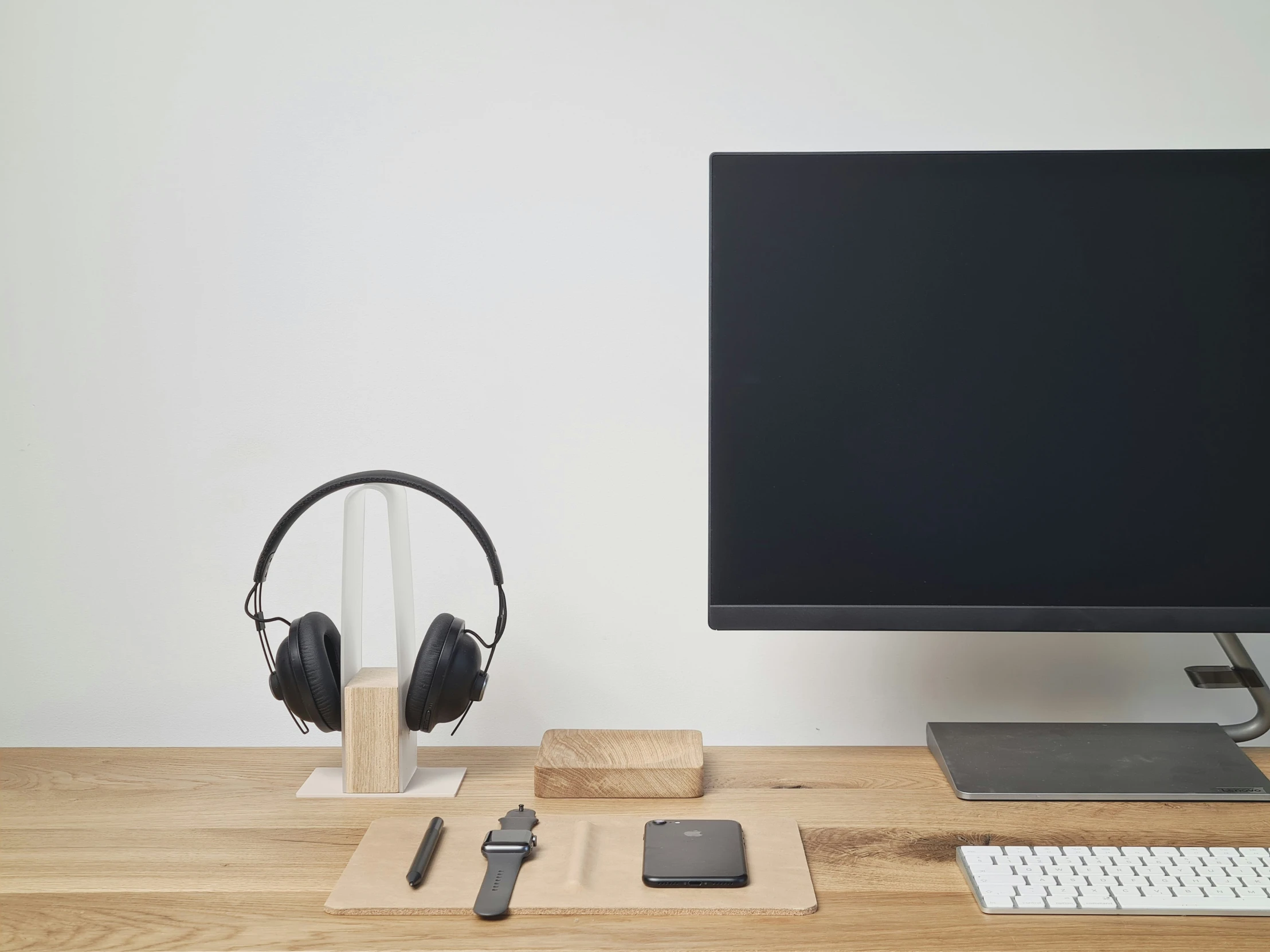 a wooden desk with computer monitor and headphones on it