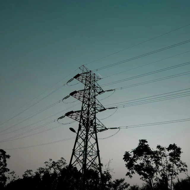 a line of high voltage power poles with a moon in the distance