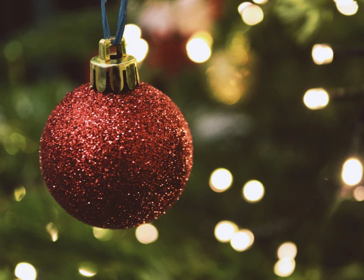 close up of red glittered ornament hanging from christmas tree