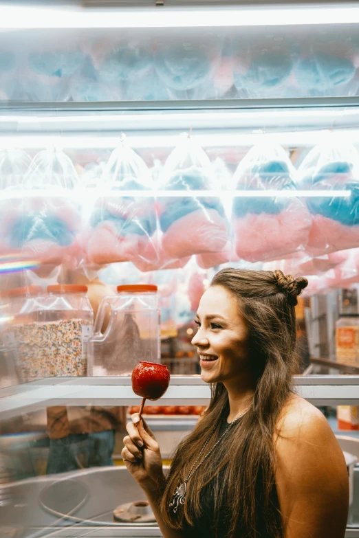 girl with pigtails holding up a candy apple