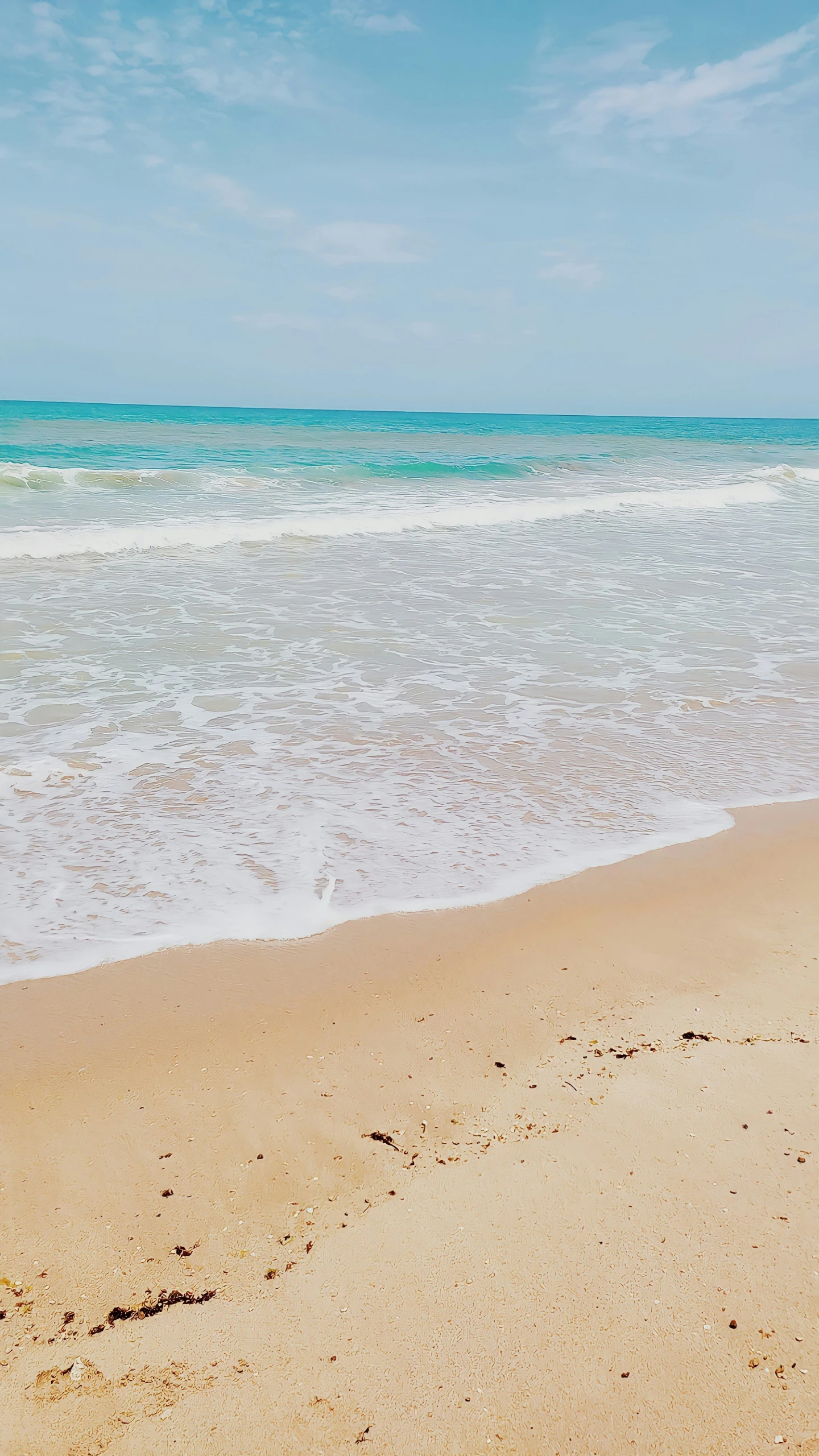 a po of the ocean water from a sandy beach