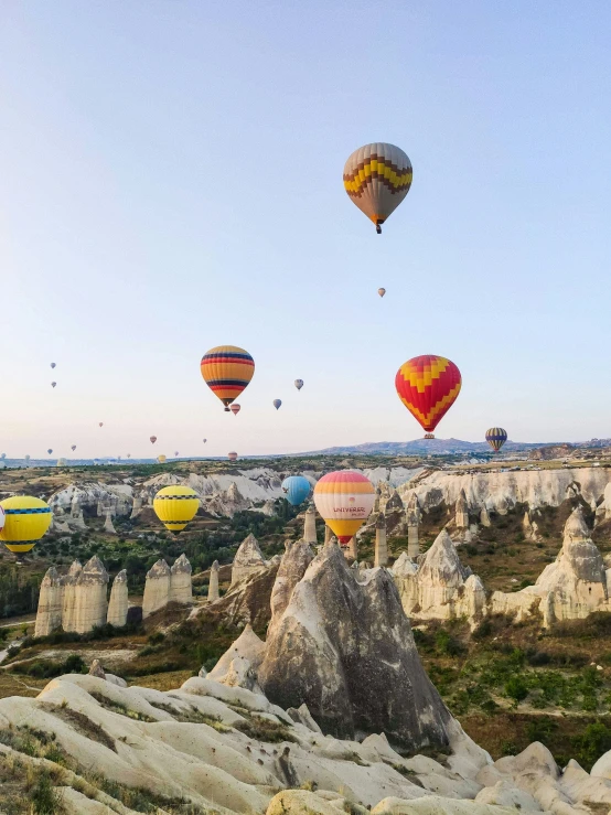 several  air balloons in the sky above some rocks