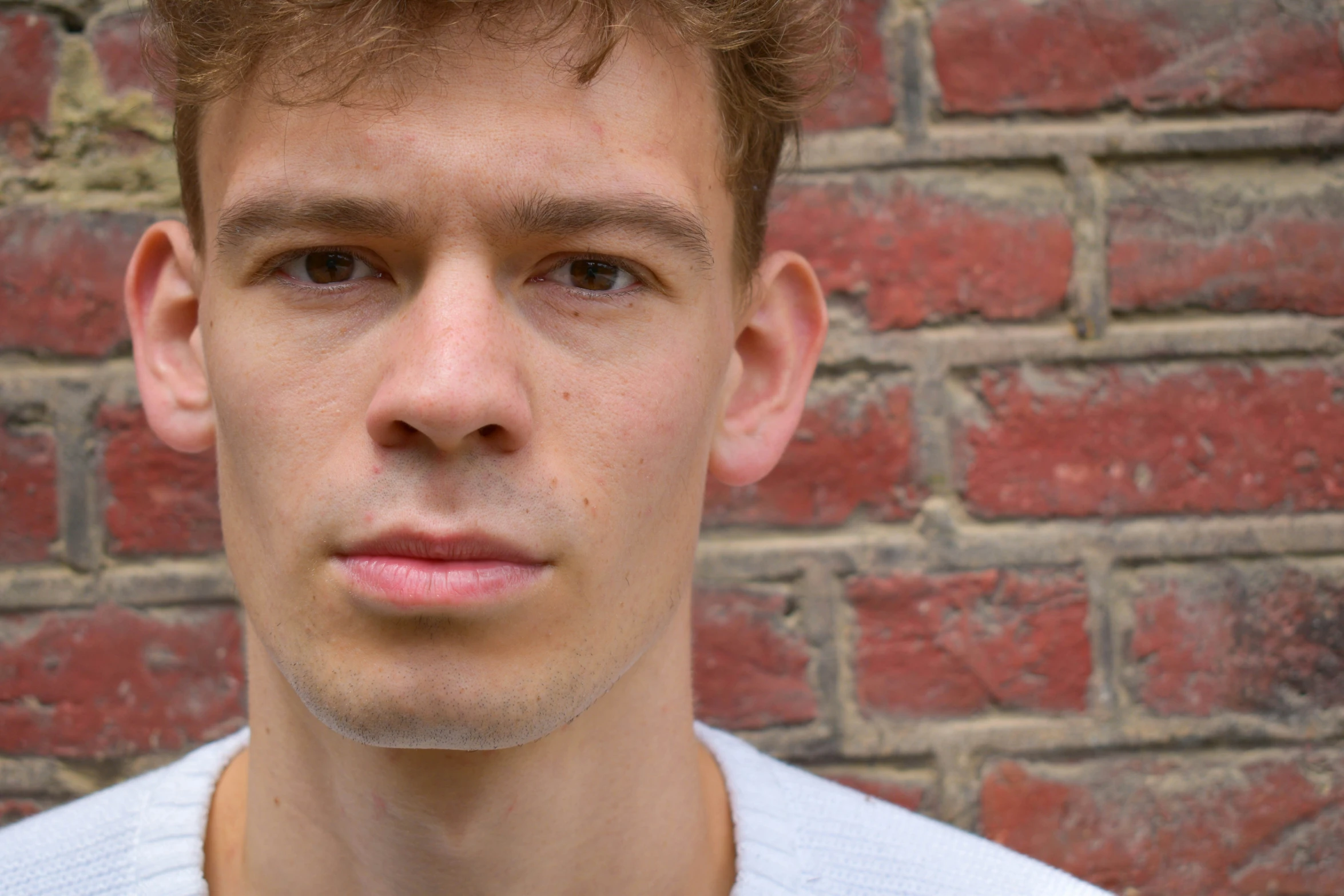 a man standing in front of a brick wall