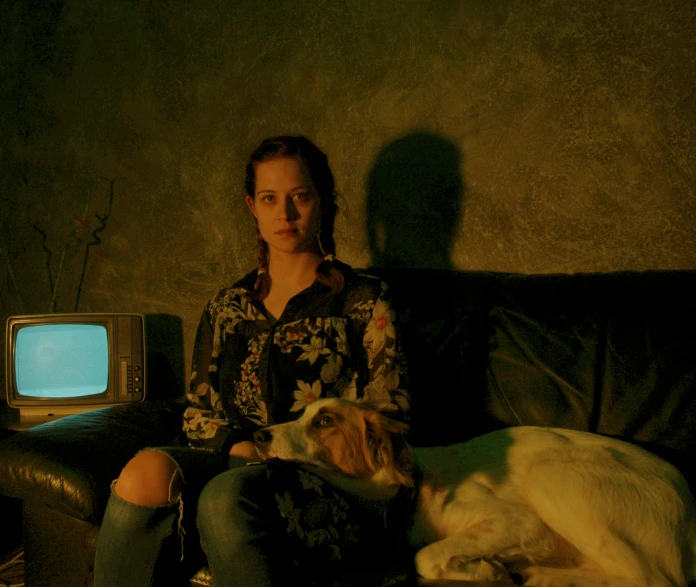 a woman sitting on the couch with a dog near by