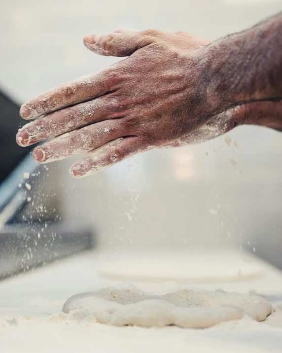 a person is sprinkling dough onto a floured dough