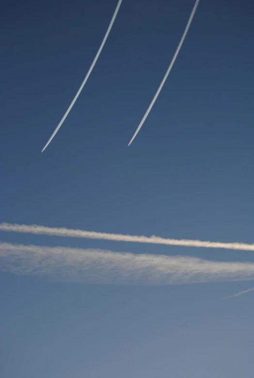 a jet flying high into the sky behind contrails