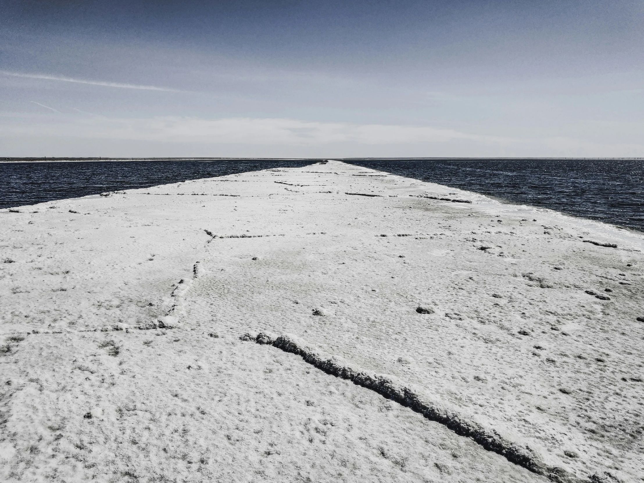 a concrete pier stretches out into the sea