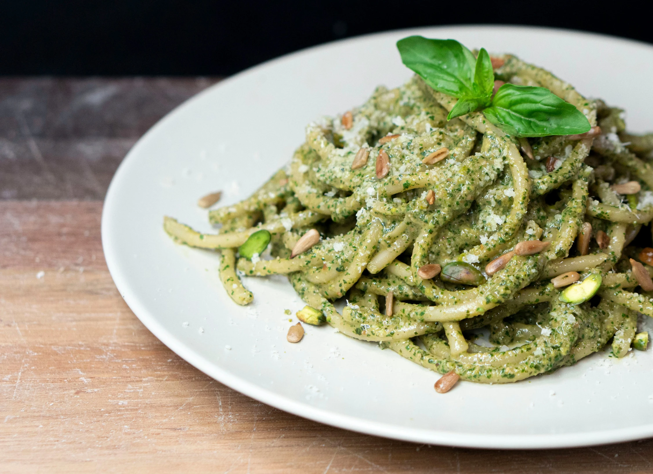 green noodles with pesto on a plate on a wooden table