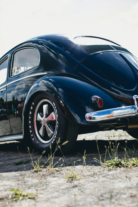 an old black car sitting in the middle of a parking lot